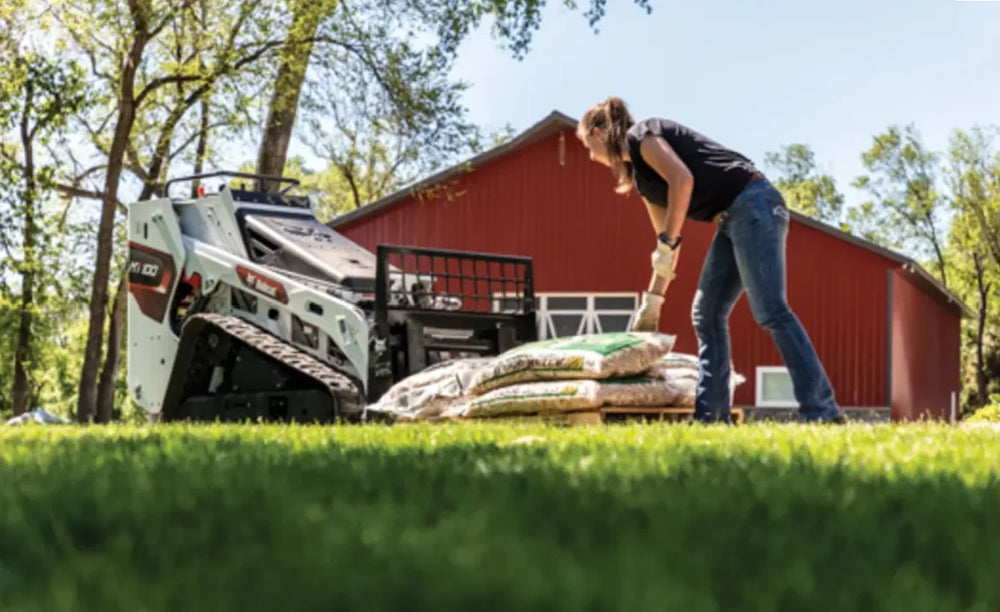woman loading bags of mulch on a skid loader