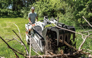 man operating a skid loader grabbing branches