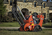 ditch witch trench digger in front of stone house