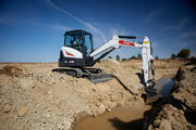 bobcat excavator digging a ditch with water in it