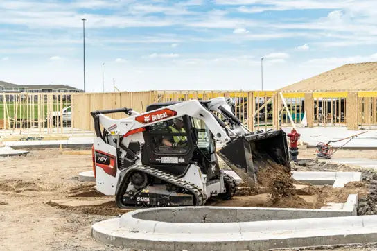 bobcat dumping dirt from a bucket on a conscrutction site