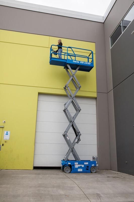 woman standing on platform of scissor lift while it is extended